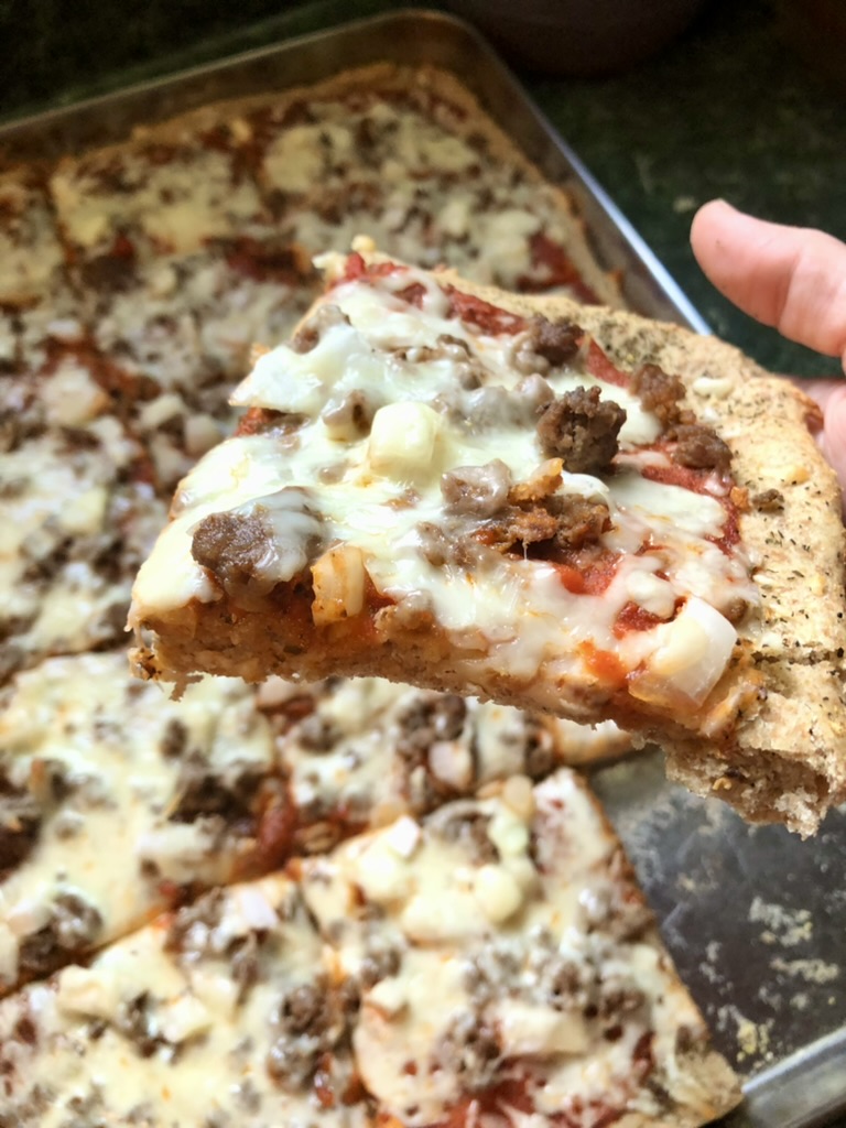 holding a finished piece of pizza